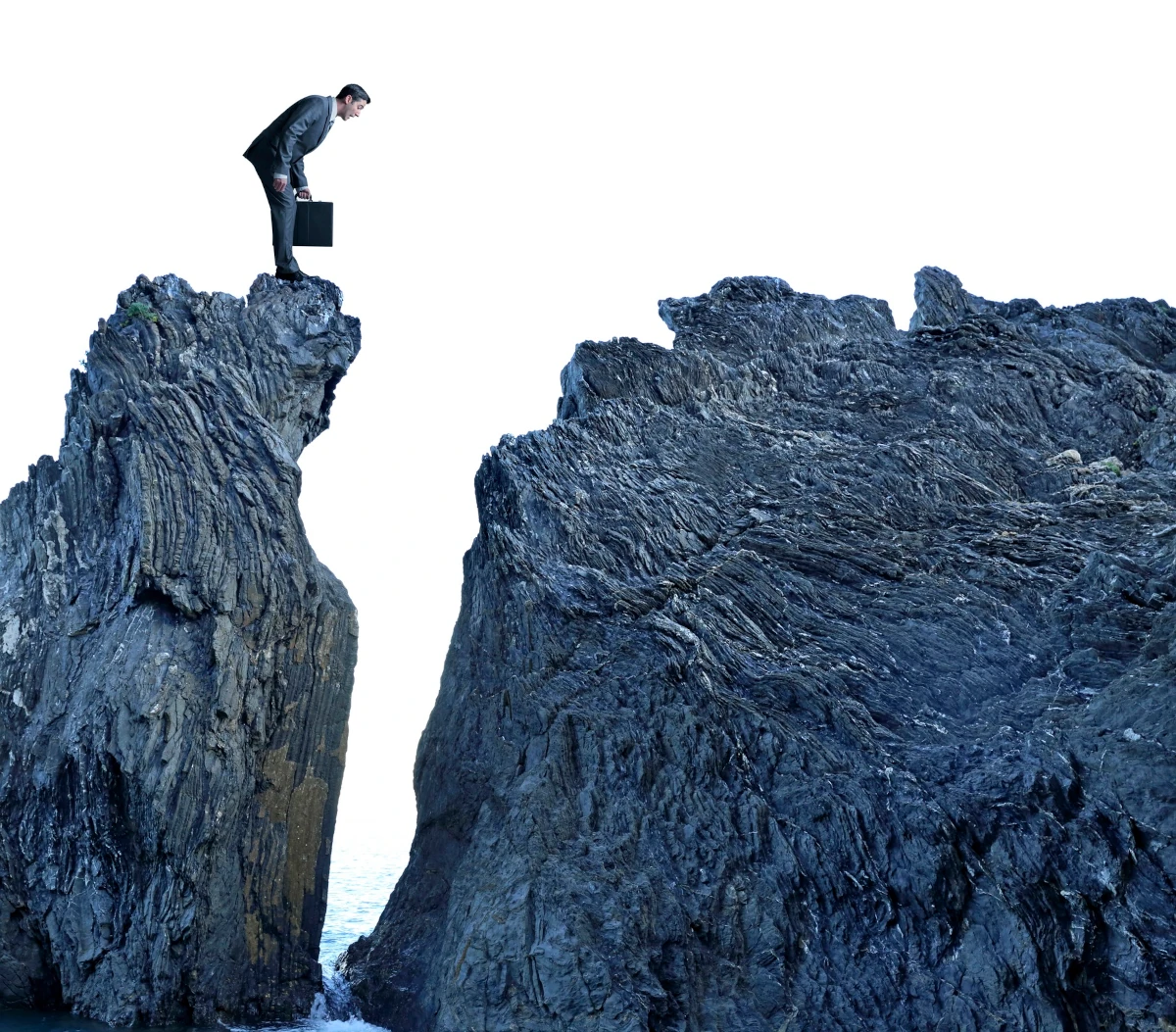 Businessman Looking Down On Top Of Rocky Cliff Above Ocean